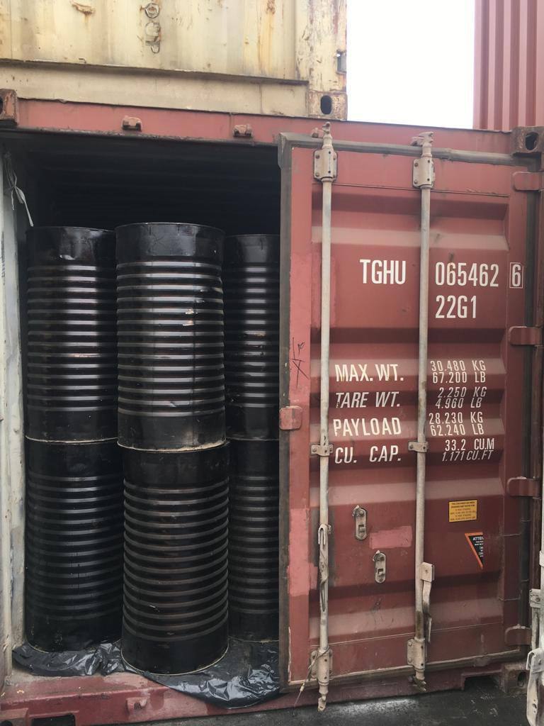 Open 20 foot container loaded with black bitumen drums beside its door plate reading maximum gross 30,480 kg, tare 2,250 kg and payload 28,215 kg
