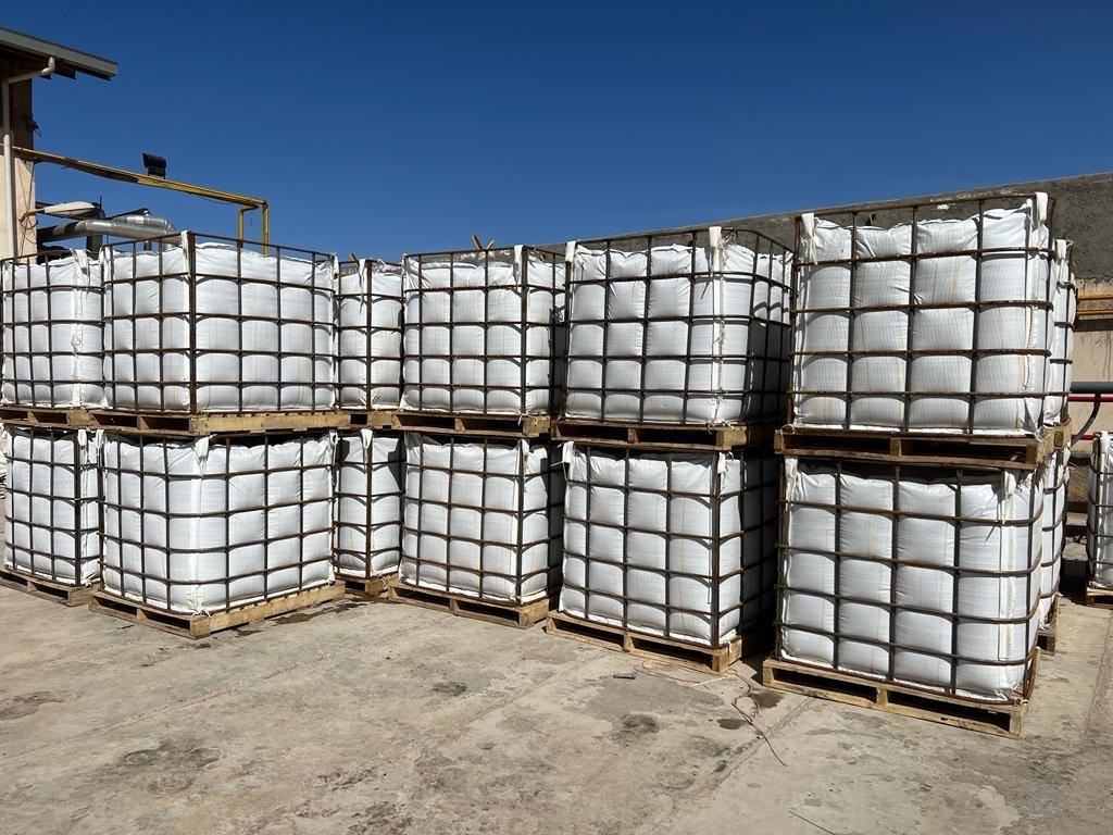 One tonne bitumen jumbo bags held in galvanised steel cage frames on timber pallets, stacked two high in a storage yard