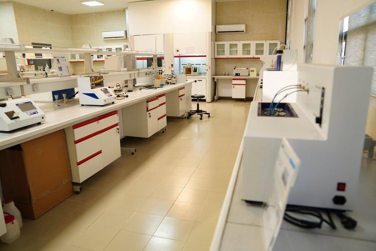 Interior of a petroleum testing laboratory with benchtop instruments, extraction hoods and sample apparatus along white benches